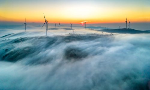 Aerial view top hill at dawn with fog covering small village in